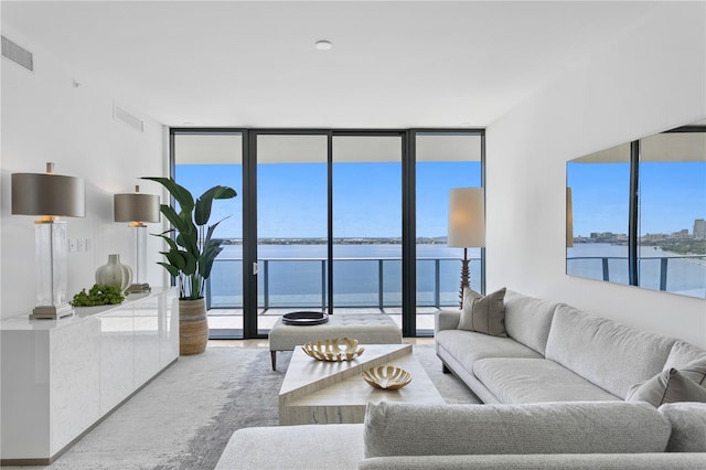 living room with a water view, visible vents, and floor to ceiling windows