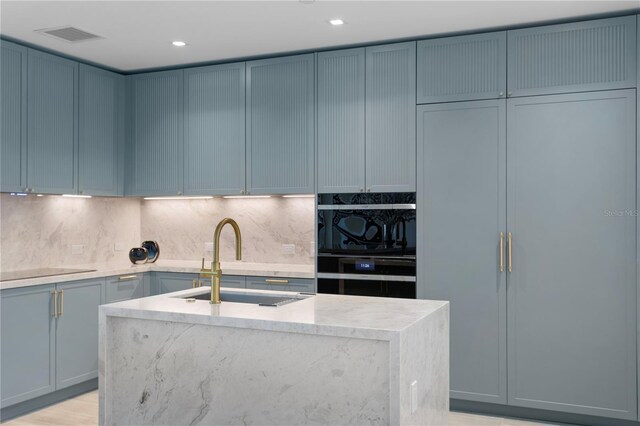 kitchen with tasteful backsplash, visible vents, a sink, light stone countertops, and black appliances