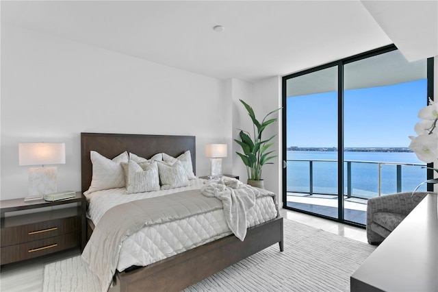 bedroom featuring access to exterior, floor to ceiling windows, and a water view