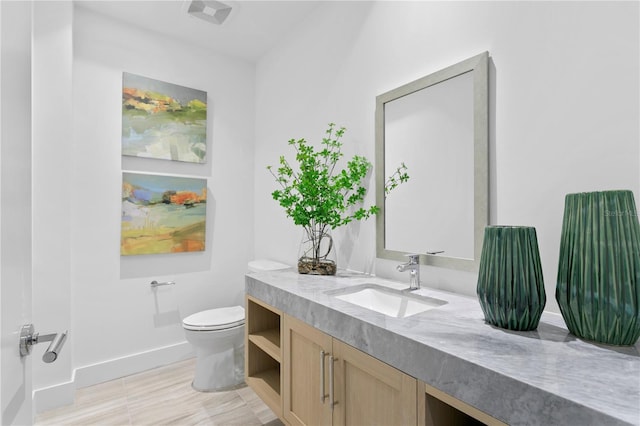 bathroom featuring baseboards, visible vents, vanity, and toilet