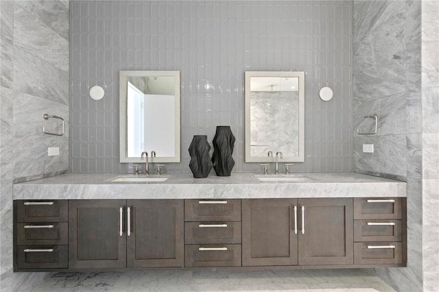 full bathroom featuring double vanity, tile walls, and a sink