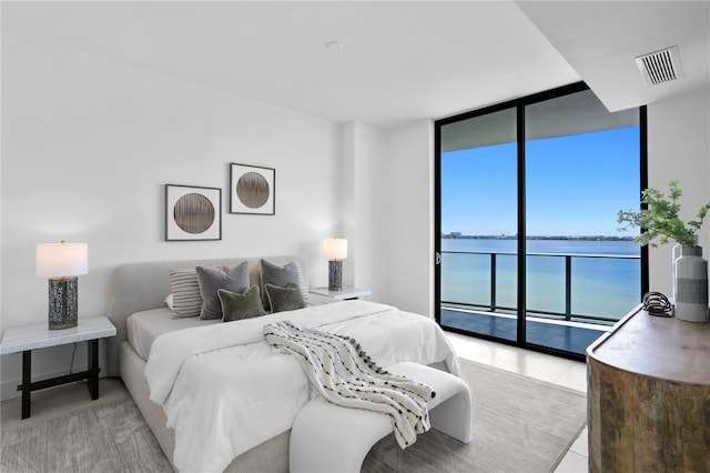 tiled bedroom featuring access to outside, expansive windows, and a water view