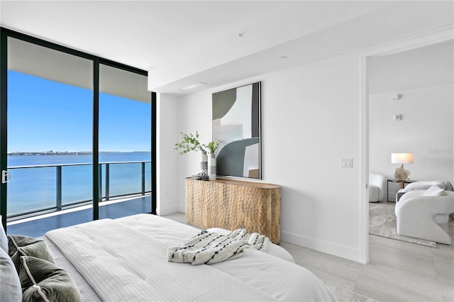 bedroom with access to outside, expansive windows, and a water view