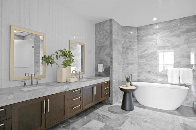 bathroom with vanity, tile walls, and a tub to relax in