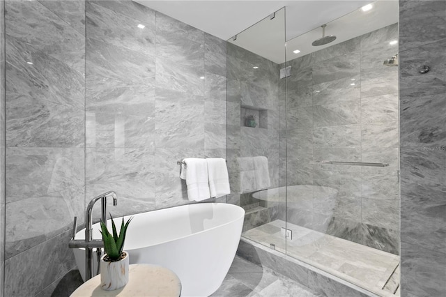 bathroom featuring tile walls and separate shower and tub