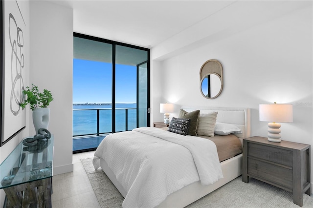 bedroom featuring expansive windows, access to exterior, and a water view