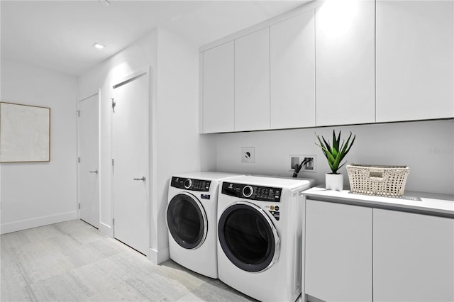 clothes washing area featuring washing machine and clothes dryer and cabinets