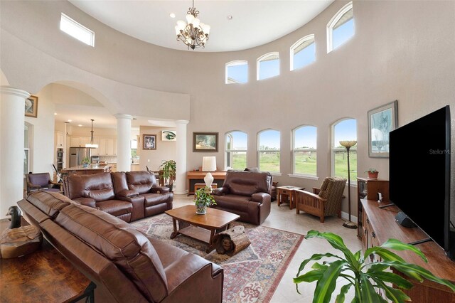 living room with an inviting chandelier, decorative columns, and a high ceiling