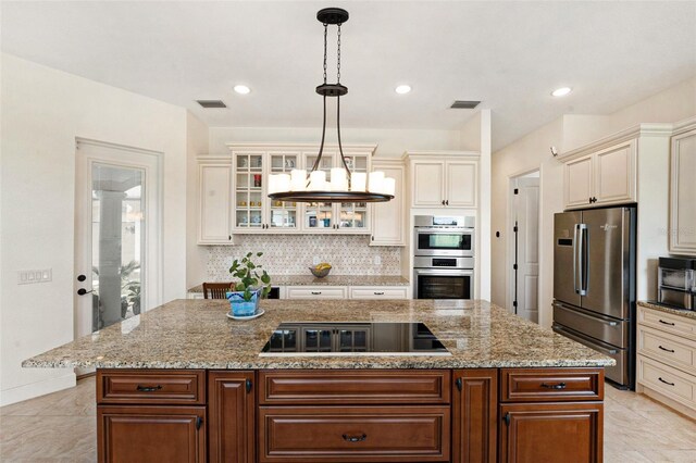 kitchen featuring cream cabinetry, hanging light fixtures, appliances with stainless steel finishes, and light tile patterned floors