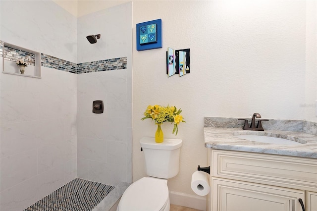 bathroom with vanity, tiled shower, and toilet