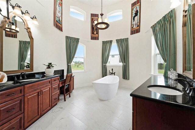 bathroom featuring an inviting chandelier, a bathing tub, dual bowl vanity, tile patterned flooring, and a towering ceiling