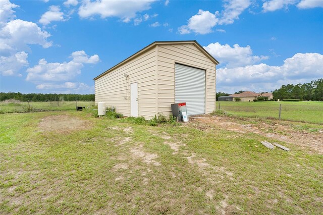 view of outbuilding with a garage, a yard, and a rural view