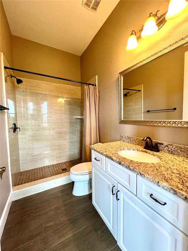 bathroom featuring walk in shower, a textured ceiling, toilet, vanity, and wood-type flooring