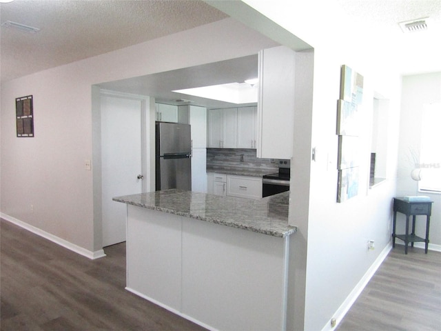 kitchen featuring backsplash, kitchen peninsula, appliances with stainless steel finishes, light stone counters, and white cabinetry