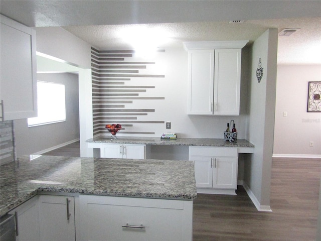 kitchen with a textured ceiling, light stone counters, white cabinets, and dark hardwood / wood-style floors