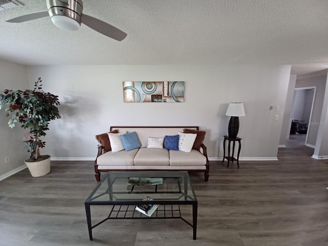 living room featuring ceiling fan, dark wood-type flooring, and a textured ceiling