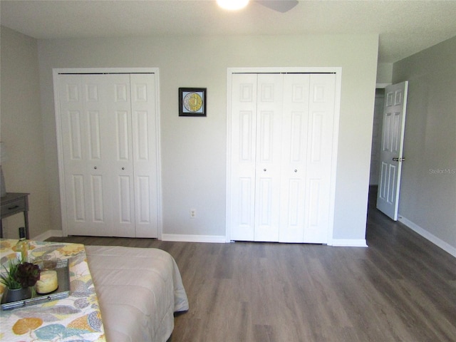 bedroom with ceiling fan, dark hardwood / wood-style floors, and two closets