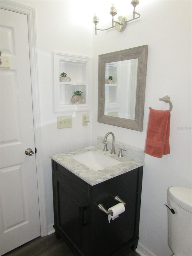 bathroom with hardwood / wood-style floors, vanity, toilet, and a notable chandelier