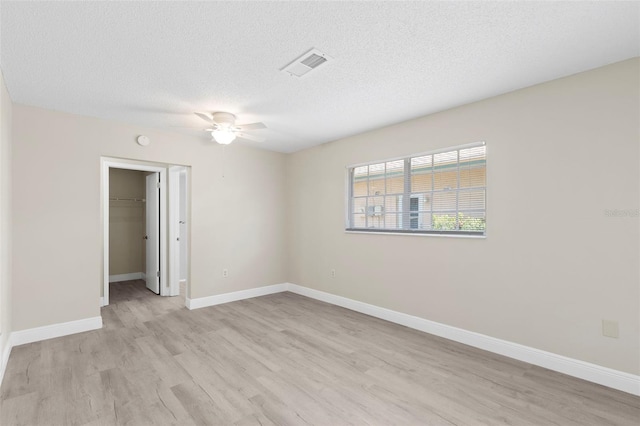 empty room featuring a textured ceiling, ceiling fan, and light wood-type flooring