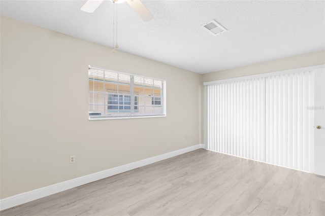 spare room featuring ceiling fan, light hardwood / wood-style flooring, and a textured ceiling