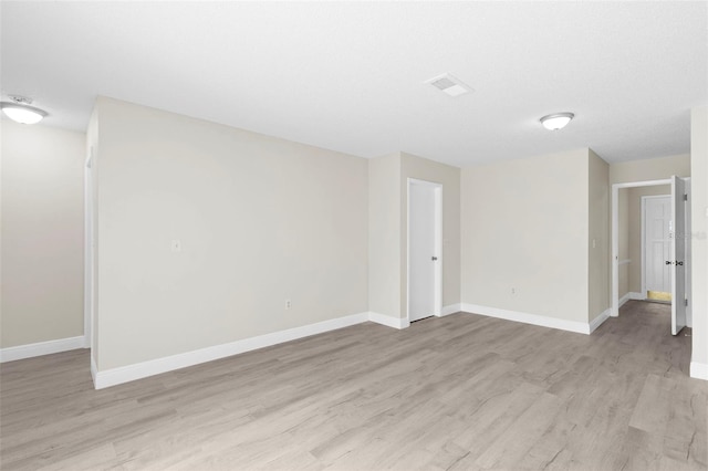 empty room with a textured ceiling and light hardwood / wood-style flooring