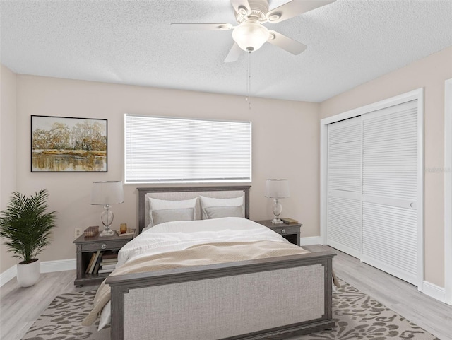 bedroom with a closet, ceiling fan, a textured ceiling, and light hardwood / wood-style flooring