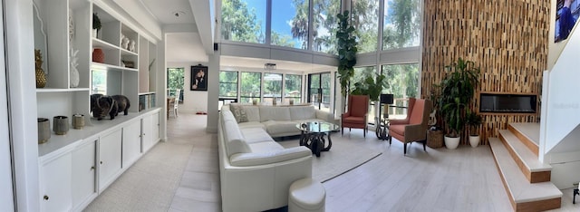 living room featuring a towering ceiling, a healthy amount of sunlight, and light hardwood / wood-style floors