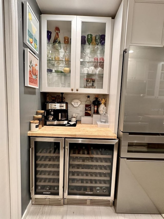 bar featuring beverage cooler and stainless steel refrigerator