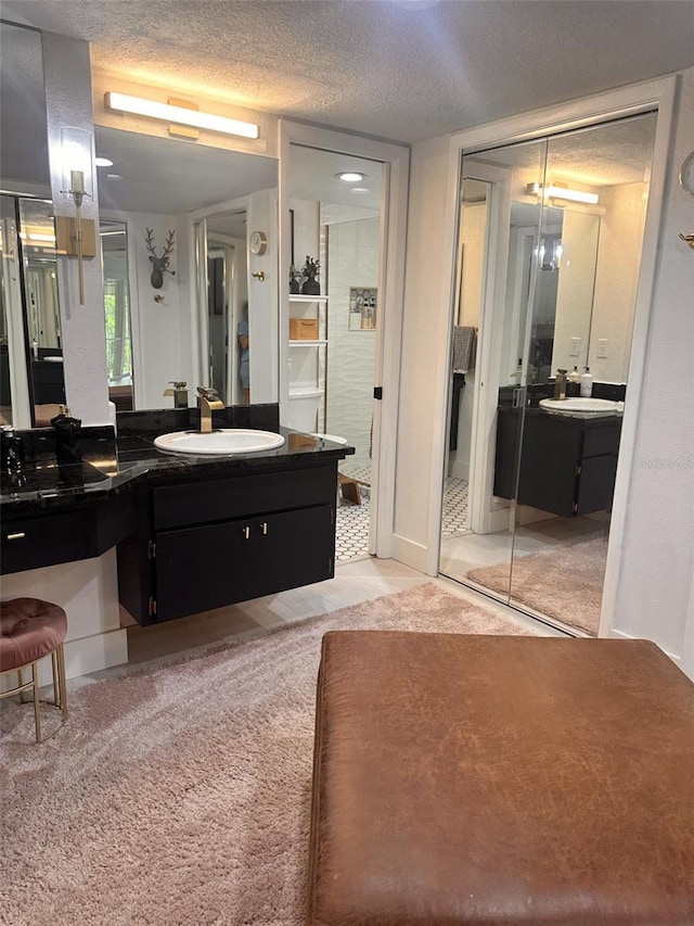 bathroom with tile patterned flooring, vanity, and a textured ceiling