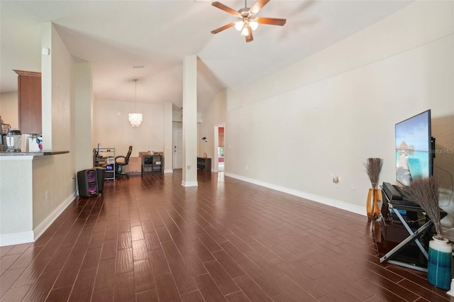 living room featuring vaulted ceiling, dark wood-type flooring, and ceiling fan with notable chandelier