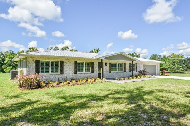 ranch-style home featuring a garage, cooling unit, and a front yard