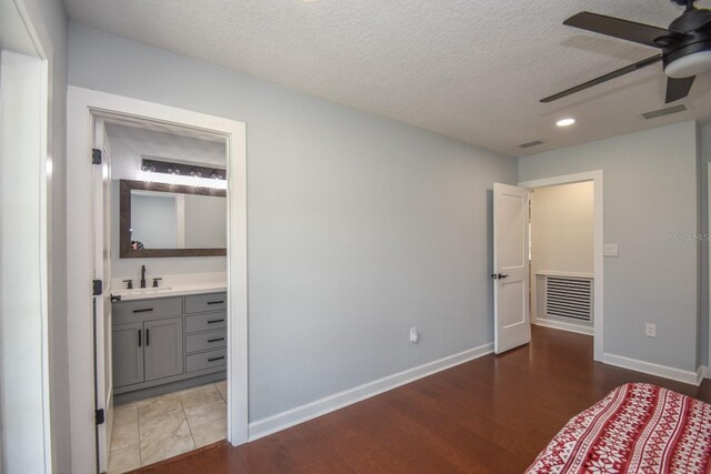 unfurnished bedroom featuring sink, connected bathroom, light tile patterned floors, a textured ceiling, and ceiling fan