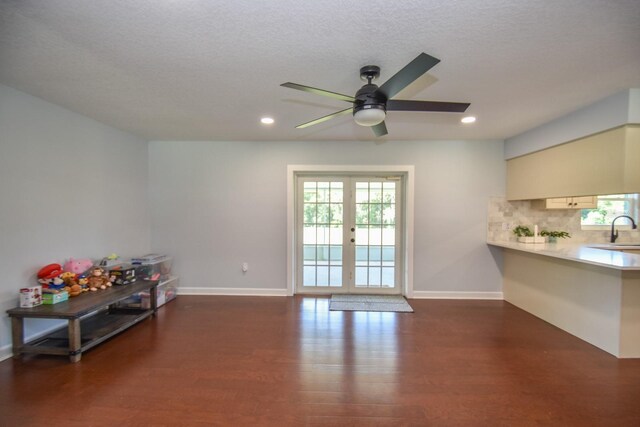 living room featuring ceiling fan, sink, french doors, a textured ceiling, and dark wood-type flooring