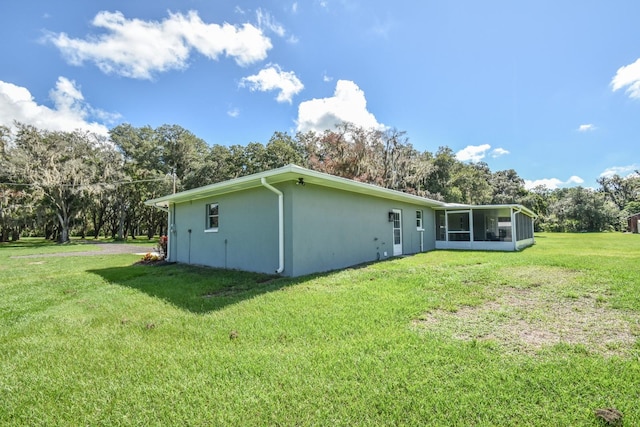 view of property exterior featuring a sunroom and a lawn