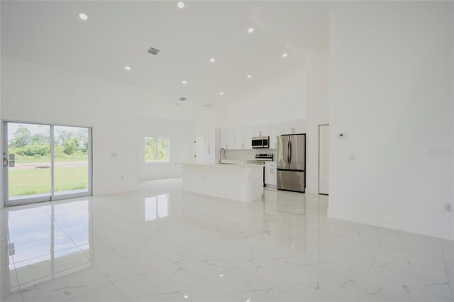unfurnished living room with baseboards, visible vents, high vaulted ceiling, marble finish floor, and a sink