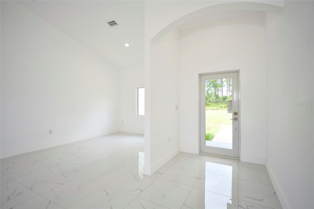 foyer entrance with baseboards, a wealth of natural light, visible vents, arched walkways, and marble finish floor