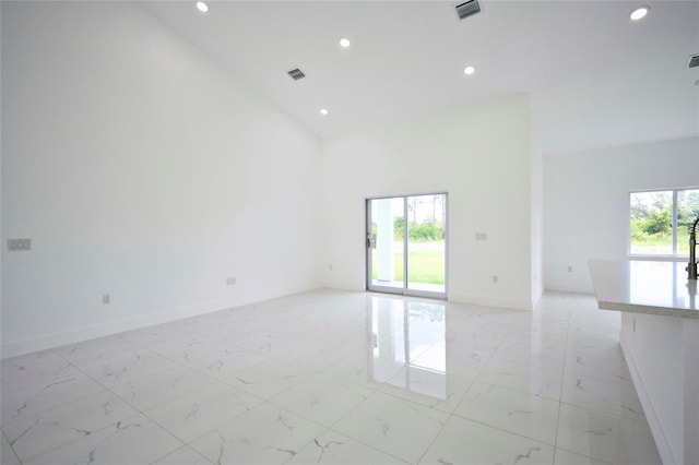 empty room with baseboards, recessed lighting, marble finish floor, and a high ceiling