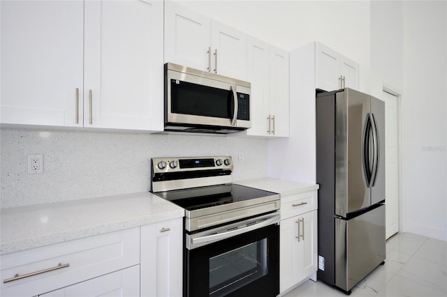 kitchen featuring stainless steel appliances, light tile patterned floors, decorative backsplash, white cabinets, and light stone counters