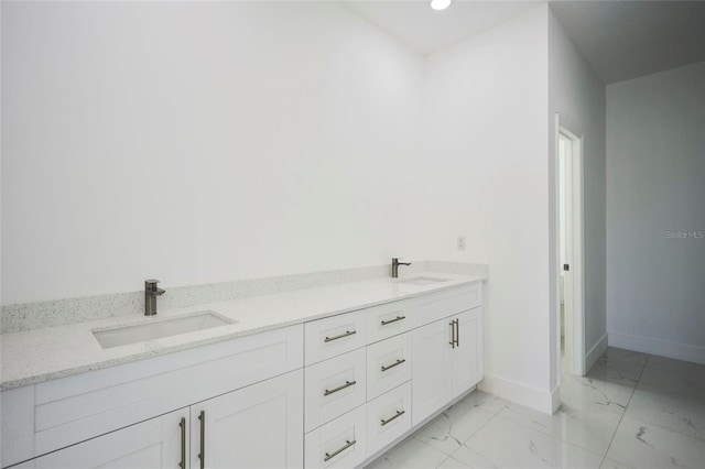 full bathroom with a sink, baseboards, double vanity, and marble finish floor