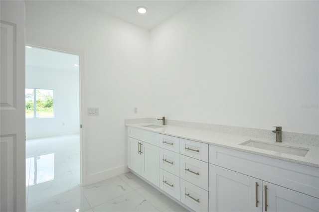 bathroom with baseboards, double vanity, marble finish floor, and a sink