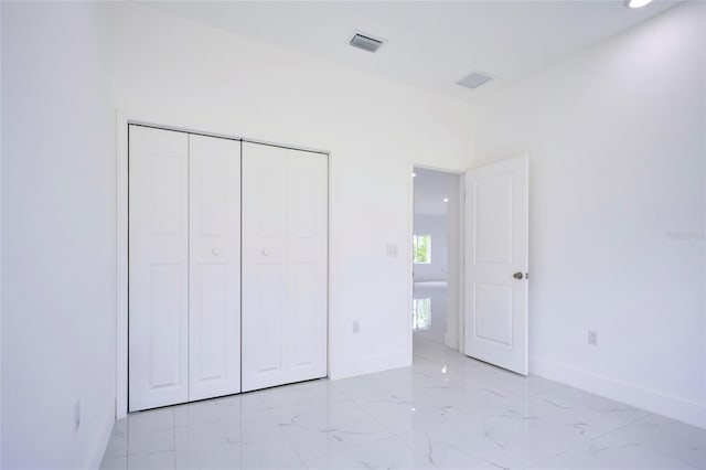 unfurnished bedroom with a closet, marble finish floor, baseboards, and visible vents