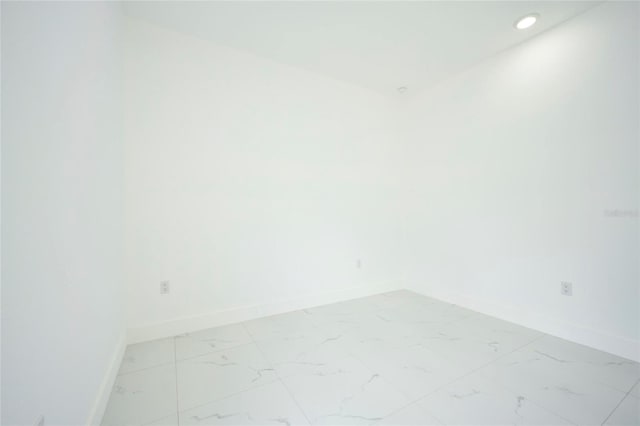 empty room featuring marble finish floor, baseboards, and recessed lighting