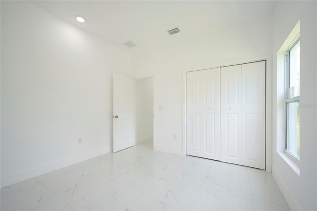 unfurnished bedroom featuring a closet, marble finish floor, baseboards, and visible vents