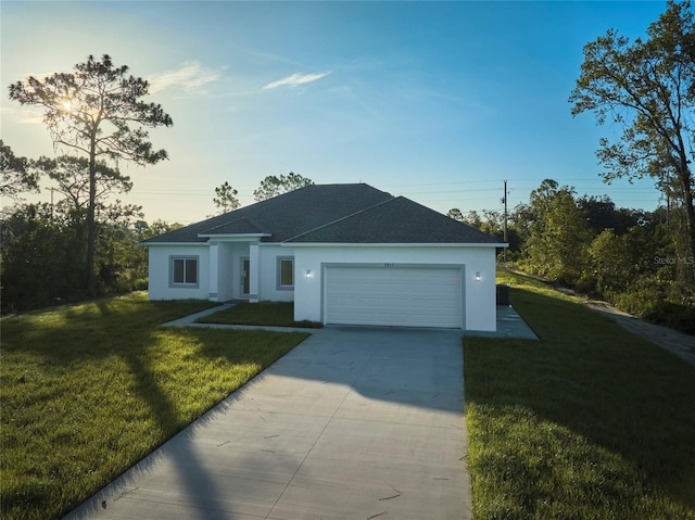 ranch-style home with a garage, stucco siding, a front yard, a shingled roof, and driveway