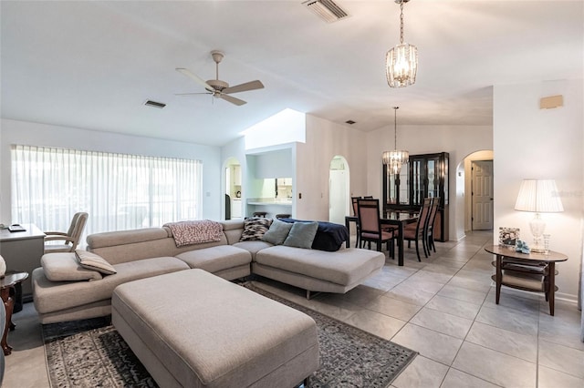 living room featuring ceiling fan with notable chandelier, light tile flooring, and lofted ceiling