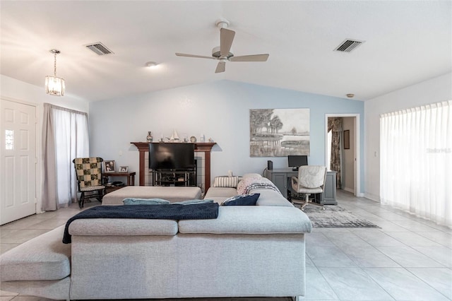 living room with plenty of natural light, ceiling fan with notable chandelier, vaulted ceiling, and light tile flooring