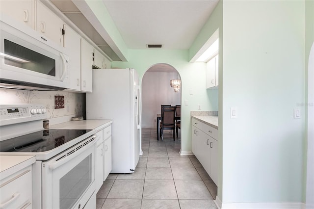 kitchen featuring white appliances, white cabinets, and light tile floors