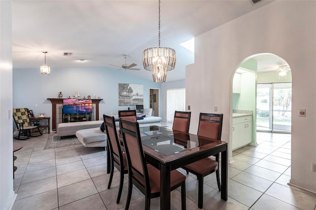 dining area with ceiling fan with notable chandelier, vaulted ceiling, and light tile flooring