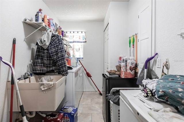 laundry room featuring sink, separate washer and dryer, a textured ceiling, and light tile floors