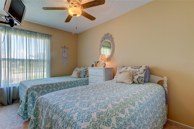 carpeted bedroom featuring ceiling fan and a textured ceiling